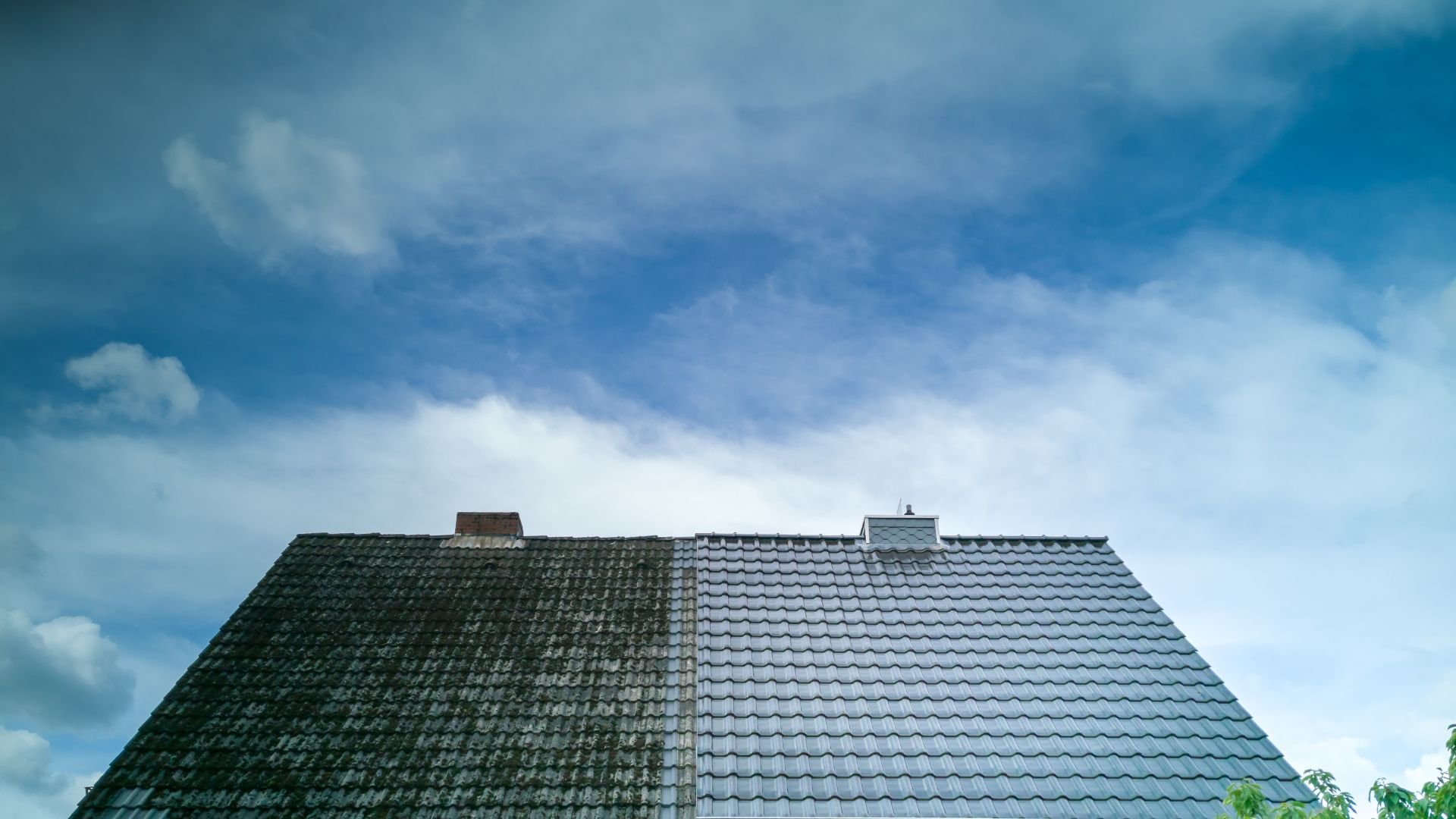 Roof with two-tone tiles against a bright blue cloudy sky