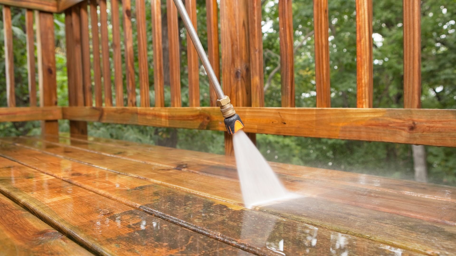Pressure washer cleaning wooden deck with spray jet of water